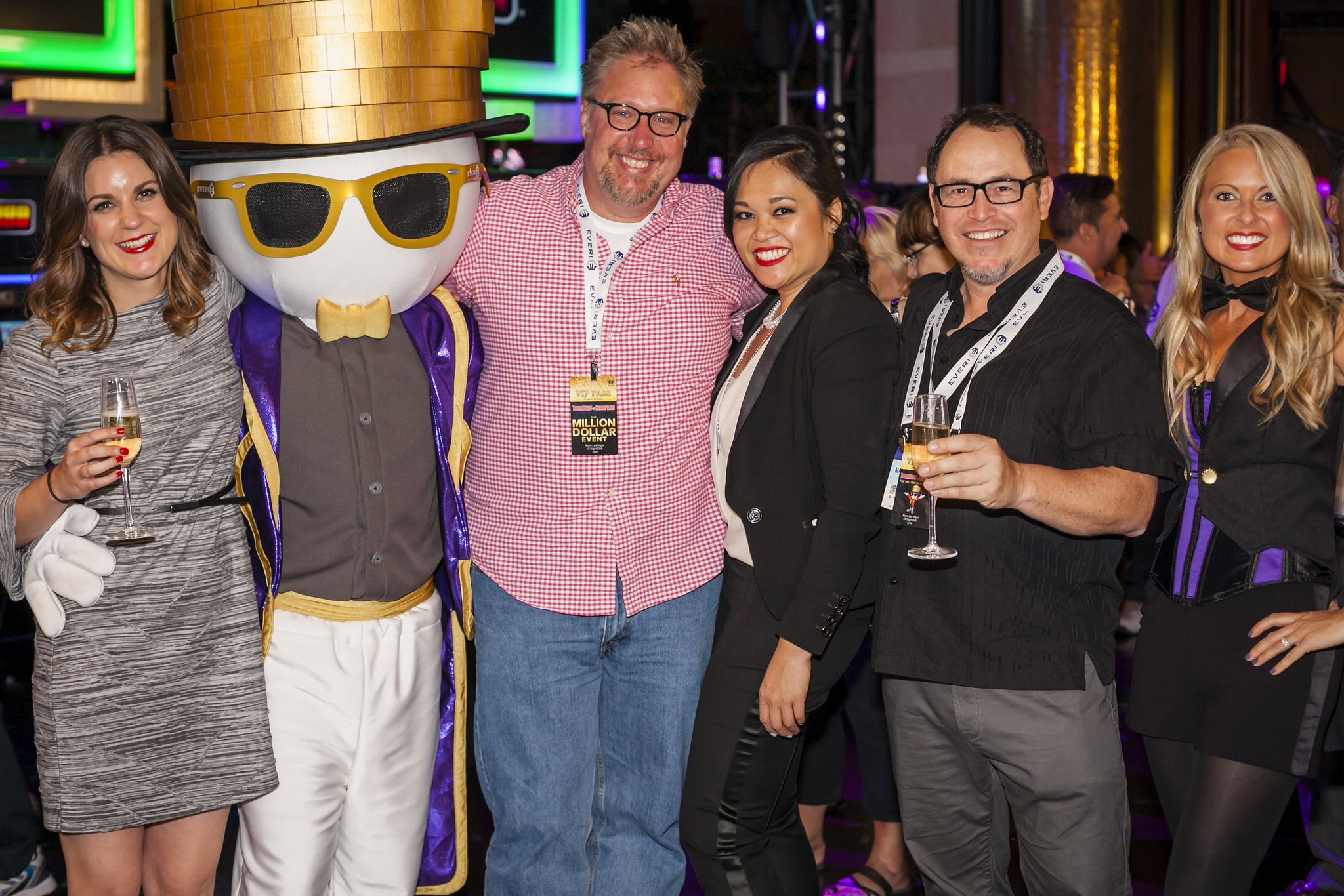 Group of people posing with a costumed character at a celebratory event.